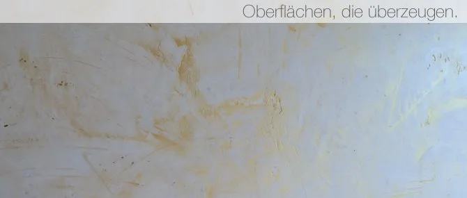 Spachtelfläche in Hellblau mit warmen Schlieren, darüber der Satz Oberflächen, die überzeugen