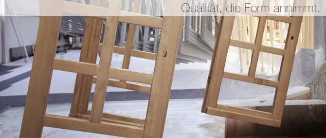 Holz-Fensterflügel stehen zum Lackieren in der Halle, darüber der Satz Qualität, die Form annimmt