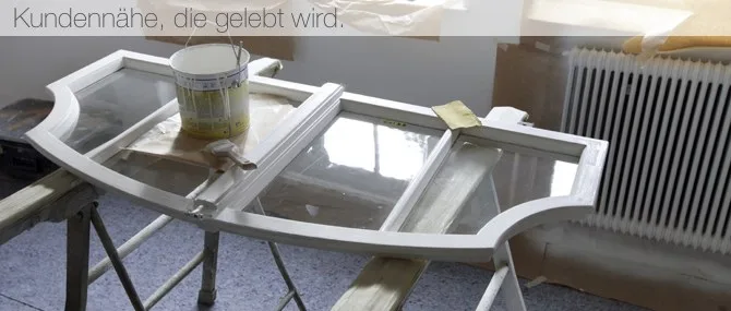 Weißer Fensterflügel auf Böcken mit Farbkübel, darüber der Satz Kundennähe, die gelebt wird