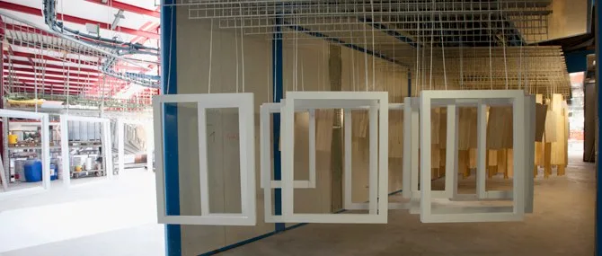 Fertig lackierte weiße Fensterrahmen hängen an der Trocknungsstrecke