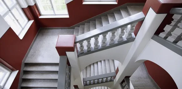 Historisches Treppenhaus im Institut St. Josef mit dunkelroten Wandflächen und weißen Balustraden