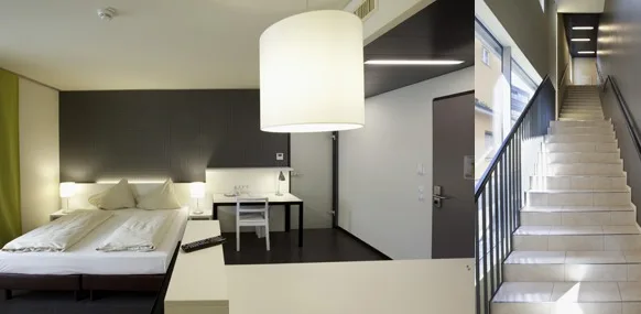 Hotelzimmer mit grün gestrichener Wandfläche, daneben ein helles Treppenhaus